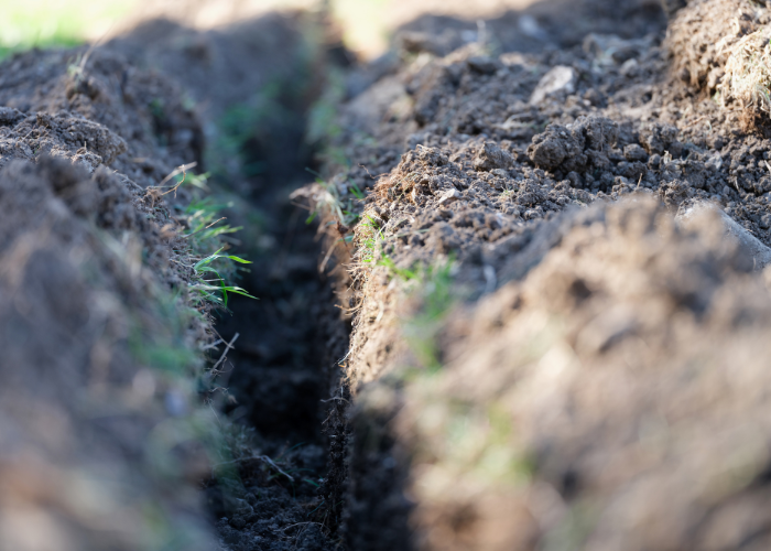 A close up of a trench made in dirt.