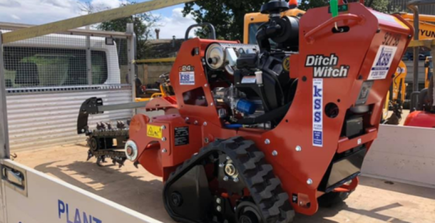A Tracked Walk Behind Trencher on the back of a flatbed truck. The trencher is decorated with a few Kss Trencher Hire stickers